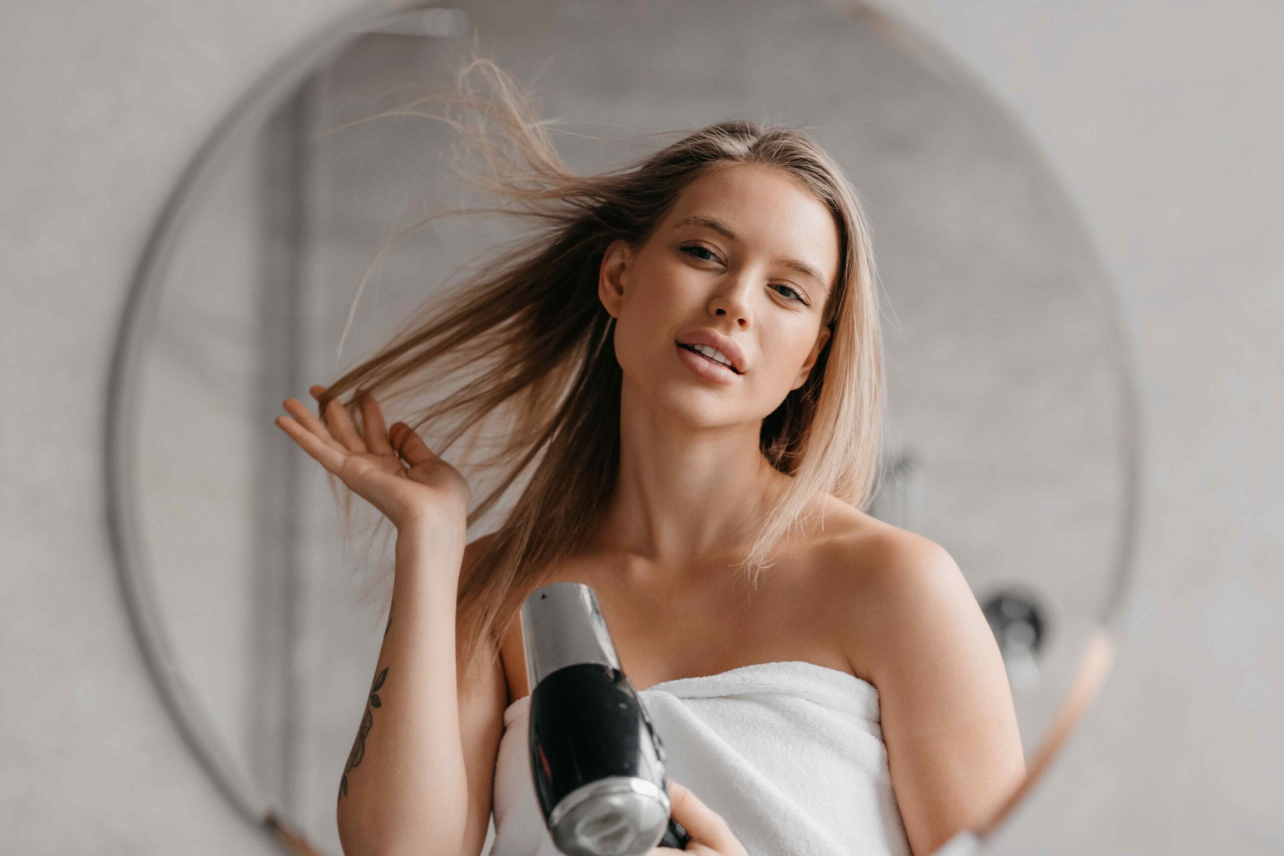 Woman blow-drying her hair in front of the mirror
